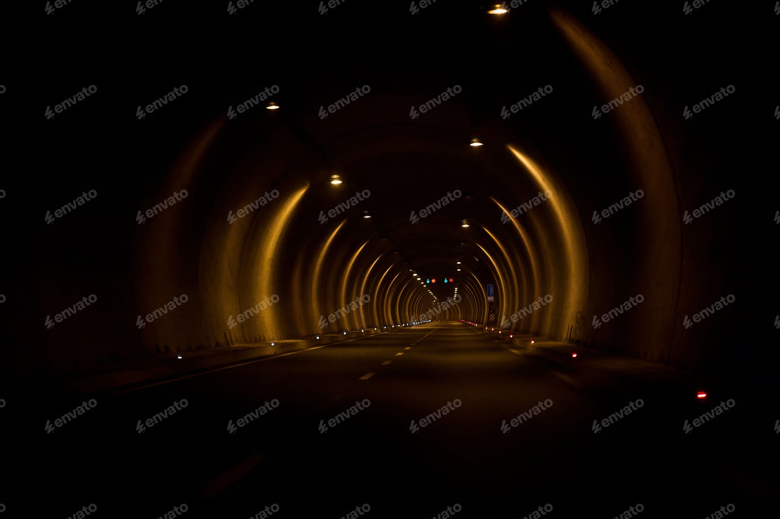 A long illuminated road tunnel curving towards distant light
